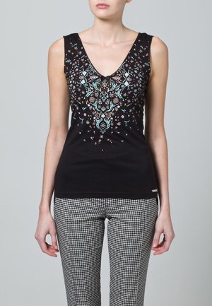 Zwart tanktop met diepe V-hals en gedetailleerde bloemenborduursels in turquoise en bruin. Gecombineerd met een pantalon in pied-de-poule patroon.