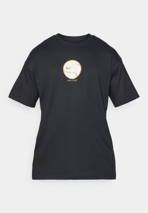 Melnā kokvilnas T-kreklā ar īsām piedurknēm ir apaļa balta un zelta Nike logo uz krūtīm, un zem tā ir teksts 'NIKE COURT'.
