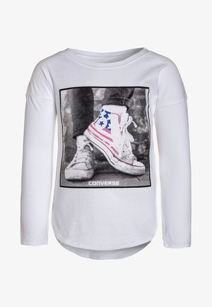 Hvid langærmet skjorte med et firkantet tryk af slidte Converse-sneakers med amerikansk flagdesign og Converse-logoet nedenunder.