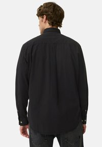 Schwarzes Langarmshirt aus glattem Stoff, mit klassischem Kragen, Knopfmanschetten und abgerundetem Saum mit einer dezenten Rückenfalte.