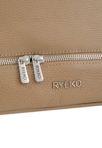 Tan gekleurde leren tas met zilveren rits en trekker, met het gegraveerde merklogo "RYŁKO" in de rechteronderhoek.
