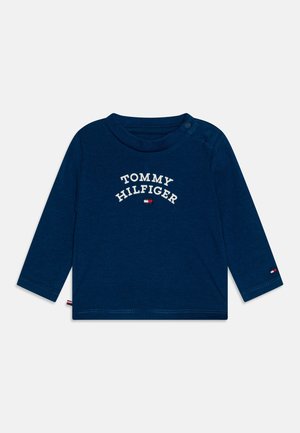 Navyblauwe longsleeve shirt van zachte stof met het "TOMMY HILFIGER" logo in het wit over de borst en een contrasterend logoaccent op de mouw.
