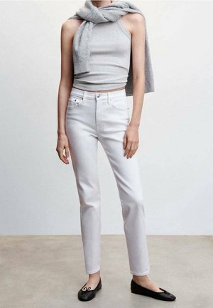 Jean droit blanc avec cinq poches, une taille haute et des accessoires en argent. Associé à un haut sans manches gris et un pull. Ballerines noires.