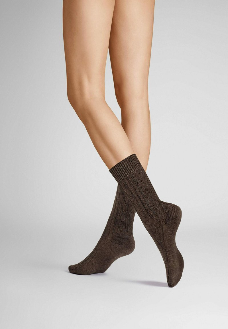 Braune Socken mit geripptem Bund, die ein komplexes Textil- und Musterspiel zeigen. Entwickelt, um eng zu sitzen und eine glatte Oberfläche zu bieten.