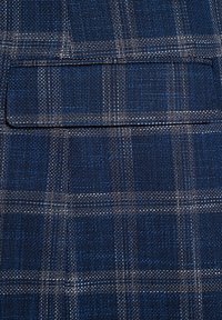 Granatowa tkanina tkana w kratkę białą i jaśniejszego odcienia niebieskiego. Z przodu prostokątna kieszeń. Teksturowana powierzchnia.