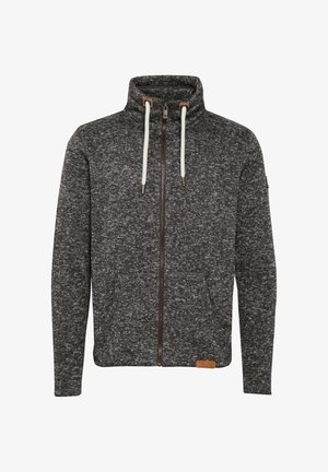 Grey zip-up hoodie with a textured knit design, high collar, contrasting white drawstrings, and side pockets. Features a leather logo patch.