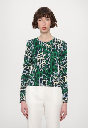 Cardigã de padrão leopardo verde e creme com mangas longas, decote redondo e fechamento frontal com botões, combinado com calças creme.