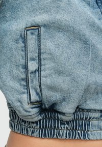 Ανοιχτό μπλε τζιν μπουφάν με ελαστική ρίγα στο τελείωμα, πλαϊνή τσέπη και διακοσμητικές ραφές σε αντίθεση. Μαλακή υφή με άνετη εφαρμογή.