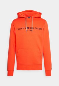 Sudadera naranja con bolsillo frontal, capucha con cordón y texto del logo en azul marino. Presenta puños y dobladillo acanalados, hecha de una tela suave.