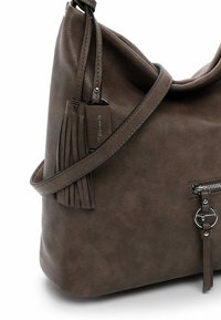 Brown faux leather shoulder bag with a slouchy design, zippered pocket, and decorative tassels attached to the strap.