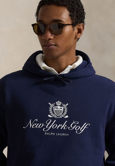 Μπλε ναυτικό φούτερ με λευκό κεντημένο λογότυπο που γράφει "New York Golf" και "RALPH LAUREN", διαθέτει κουκούλα με κορδόνι και άνετη εφαρμογή.
