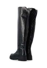 Botas negras hasta la rodilla hechas de material brillante con patrón de cocodrilo, que cuentan con una suela gruesa y un diseño elegante con un ligero ensanchamiento en la parte superior.
