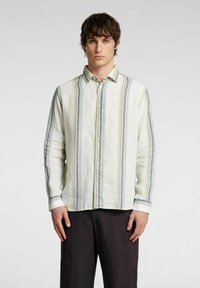 Camicetta chiara con bottoni realizzata in lino. Presenta righe verticali in grigio, giallo e blu, con maniche lunghe e colletto.