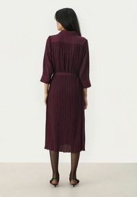 Mauve pleated dress with a collar, three-quarter sleeves, and a tie belt, featuring a flowy texture that reaches mid-calf length.