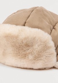 Chapeau en peluche marron avec une bande en fausse fourrure beige clair et douce. Le design rembourré présente une texture matelassée pour la chaleur et le confort.