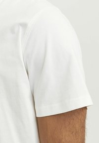 White cotton t-shirt featuring a short sleeve, smooth texture, and a casual fit, with minimal stitching details along the seams.
