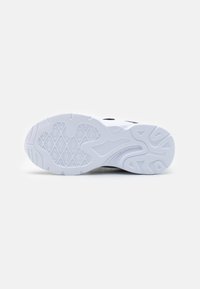 Semelle d'une chaussure de sport blanche avec des motifs de semelle géométriques et ondulés sur un fond blanc uni.