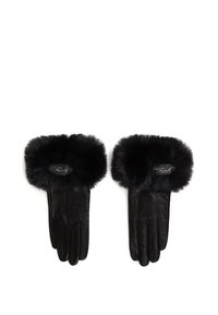 Sorte lærhansker med en fluffy svart faux fur mansjett. Har et ovalt logo-patch ved håndleddet. Glatt tekstur med en strukturert form.