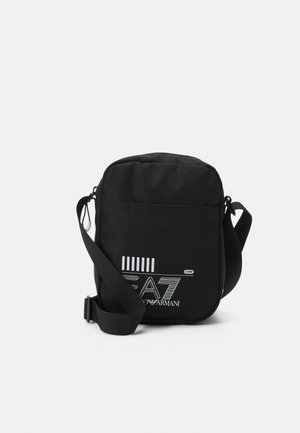 Zwarte crossbodytas met verstelbare riem en wit EA7 Emporio Armani-logo op de voorkant, tegen een witte achtergrond.