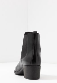 Czarne skórzane botki za kostkę z elastycznymi panelami bocznymi, zaokrąglonym noskiem i niskim obcasem. Gładka faktura z minimalnymi detalami w szwie.