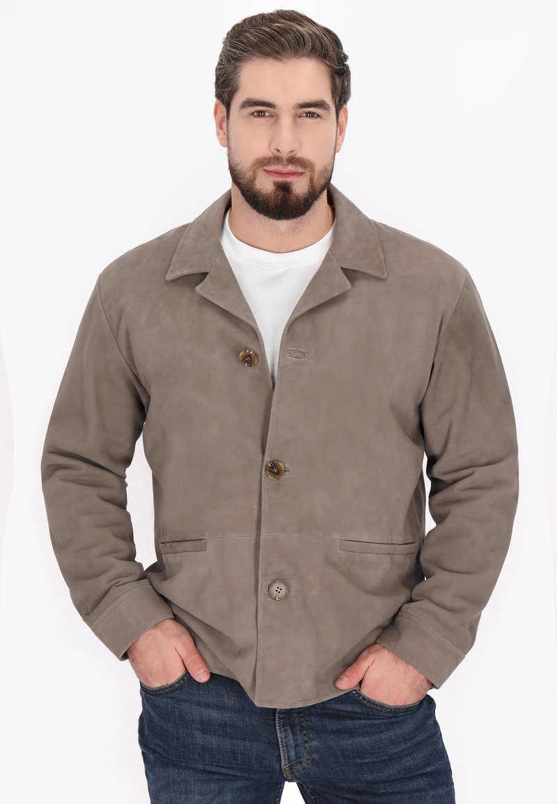 Jachetă din suede maro cu guler decupat, două închideri cu nasturi și buzunare frontale. Textură netedă, design ajustat și detalii de cusătură vizibile.