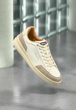 Zapatillas deportivas de cuero blanco con detalles en ante beige, puntera redonda, cordones planos y suela de goma texturizada. Logo estampado en el lateral.