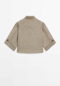 Beige linned skjorte med krave, lange ærmer rullet op ved manchetten, rygbælg og en let buet saumbredde. Enkel, tekstureret stof.