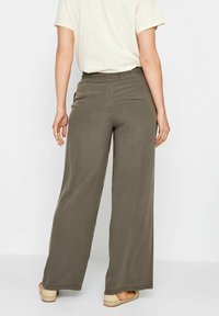 Wijd uitlopende broek van olijfgroene stof, met een elastische tailleband en eenvoudige stiksels langs de zoom.