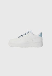 White Nike Air Force 1 sneakers with a smooth leather upper, light blue accents on the heel, and gray laces. Round toe and textured sole.