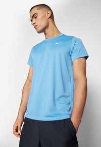 Hele sinine spordist Kõnnits, mis on valmistatud niiskust imavast kangast. Omab lühikesi varrukaid ja valget Nike logo ülemises vasakus servas.
