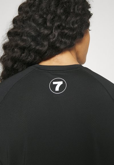 Black sports shirt featuring a round neck, raglan sleeves, and a circular white logo with the number 7 on the back. Textured fabric.