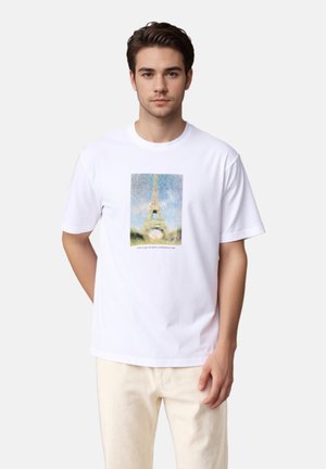 Fehér pamut póló, amelyet az Eiffel-torony nyomtatott illusztrációja díszít, lágy színekkel és texturált háttérrel. Rövid ujjú és kerek nyakú.