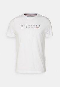 Bílé tričko s krátkým rukávem a kulatým výstřihem s textem "HILFIGER NEW YORK" a malými grafickými detaily v červené, bílé a černé barvě na hrudi.