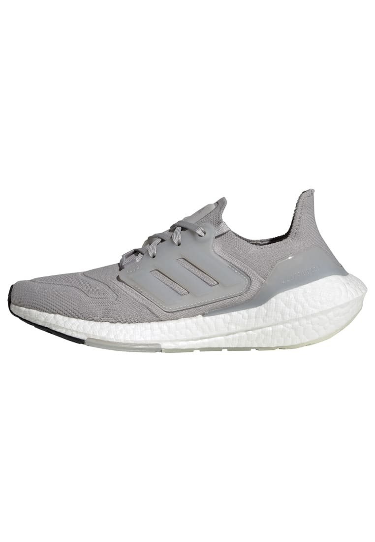 Sneaker atletico grigio con tomaia in rete texturizzata, accenti a tre strisce, chiusura con lacci e una spessa suola bianca imbottita.