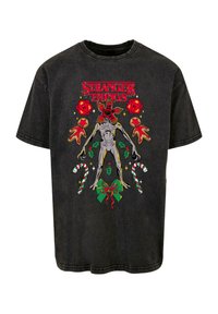 Černé bavlněné tričko s barevným potiskem "Stranger Things", zobrazující mimozemskou postavu, cukrové hůlky a vánoční motivy.