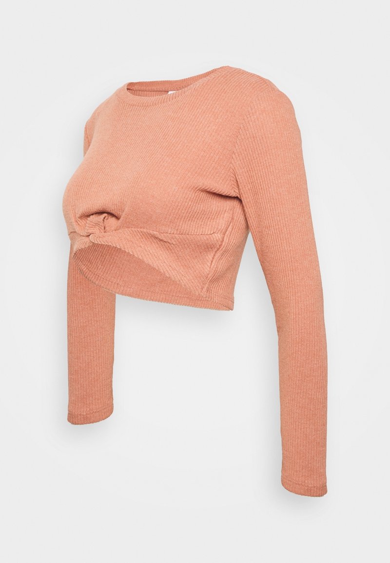 Haut court à manches longues et coupe ajustée en tissu côtelé texturé, léger pêche. Présente un détail noué à l'avant pour un look décontracté.