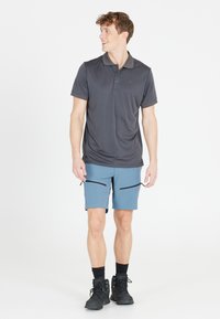Mörkgrå kortärmad pikétröja för män med krage, ihopkopplad med ljusblå shorts med dragkedjefickor. Svarta vandringsskor.