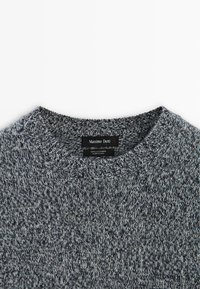 Maglione grigio in cashmere con scollo rotondo, caratterizzato da un motivo a maglia testurizzata. Etichetta del marchio "Massimo Dutti" visibile all'interno del colletto.