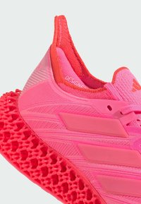 Scarpa sportiva rosa con tomaia in mesh testurizzato e suola a motivo esagonale. Include tre strisce laterali testurizzate e un collare imbottito.
