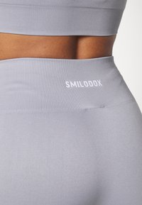 Jasnoszare legginsy wysoki stan z prążkowanym wzorem i białym logo "SMILODOX" na pasie. Dopasowany krój podkreśla sylwetkę.