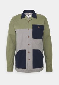 Giacca con bottoni, caratterizzata da blocchi di colore verde, grigio e blu navy. Realizzata in un tessuto resistente, presenta una tasca sul petto e due tasche laterali. Bottoni marroni.