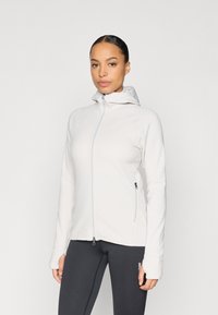 Hellgraue Jacke mit Reißverschluss und Kapuze, aus glattem, dehnbarem Stoff; verfügt über Seitentaschen und Daumenlöcher an den Bündchen.