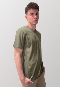 T-shirt in cotone verde oliva con maniche corte, collo a giro e vestibilità comoda. Nessun motivo o dettaglio hardware visibile. Texture liscia.