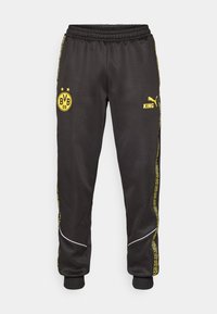 Sorte træningsbukser med gule Borussia Dortmund BVB 09 og Puma King logoer, elastisk talje, og mønstrede gule side-striber.