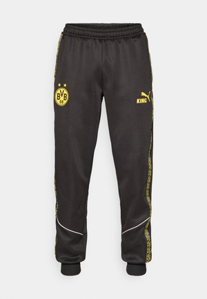 Fekete sportnadrág sárga Borussia Dortmund BVB 09 és Puma King logókkal, elasztikus derékkal és mintás sárga oldalsó csíkokkal.