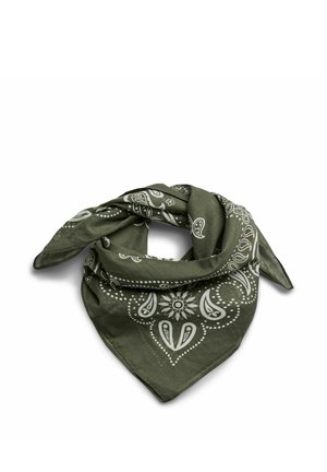 Femme portant un foulard vert à motifs et un pull en maille gris, une main posée sur la tête, regardant sur le côté.