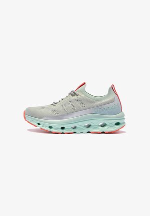 Zapatilla deportiva gris claro con suela gruesa verde menta, detalles en naranja y cordones estampados, vista de lado sobre fondo blanco.