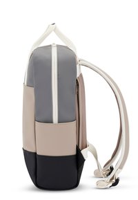 Multi-colored backpack featuring gray, beige, and black sections with a smooth finish, white zippers, and textured side pockets.