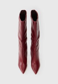 Par de botas altas de cuero burdeos, con punta afilada y cremalleras laterales, mostradas desde arriba sobre un fondo blanco.