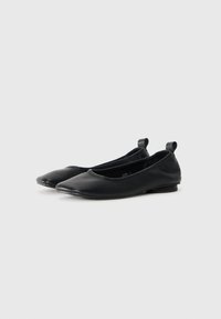 Ballerines noires en cuir lisse, présentant un bout arrondi, un talon bas et une boucle à l'arrière pour un enfilage facile. Design minimaliste avec des accents subtils.